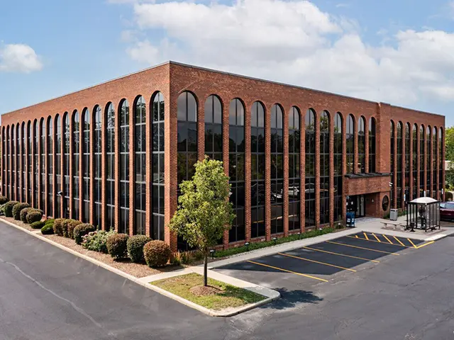 A large brick building with many windows and trees.