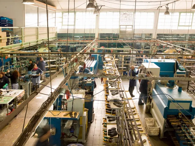 A factory floor with many workers working on machines.