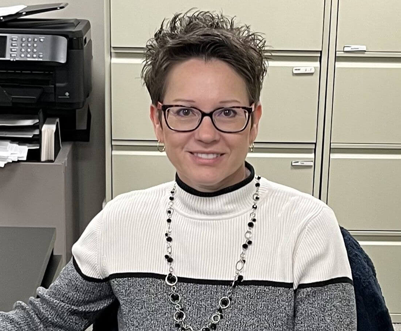 A woman with short hair wearing glasses and a sweater.